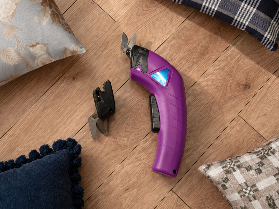 cordless-electric-scissor-placed-on-a-hardwood-flor-with-pillows-around-it